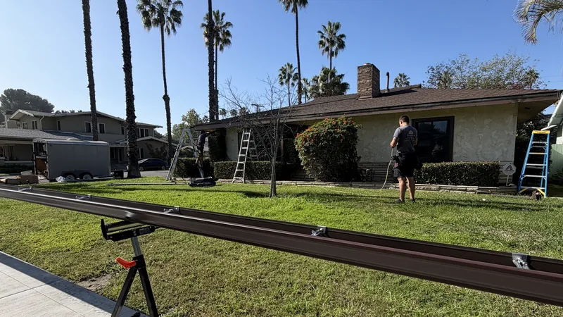 Belfour Gutters installer working beside a long gutter section at a residential jobsite
