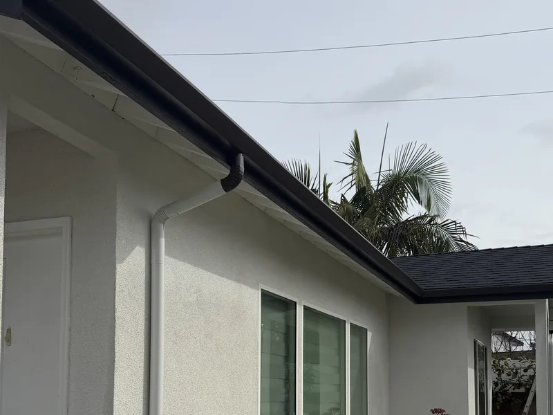 Black gutter with white downspout installed on an Irvine home