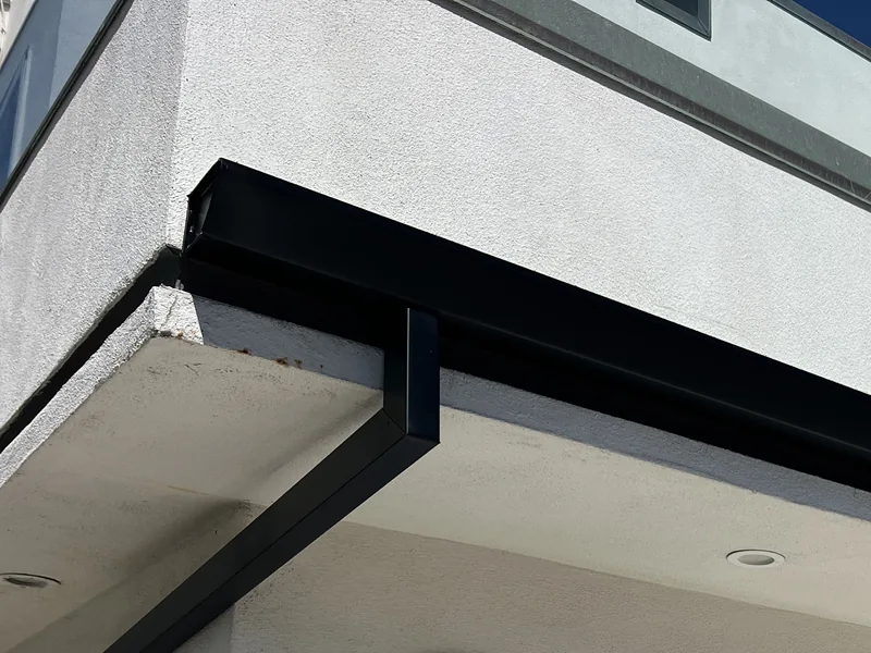 Black gutter installed along a modern white home in Newport Beach
